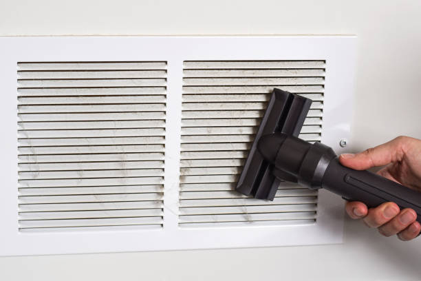 Person's hand vacuuming dirty return air vents
